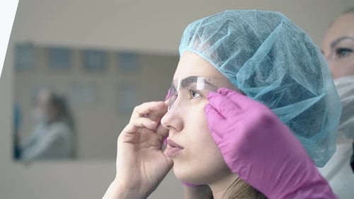 Makeup Artist Adjusts Eyebrow Ruler on Woman