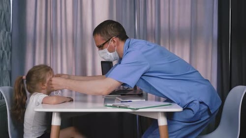 Doctor in Glasses Puts Mask on Little Cute Girl in Hospital