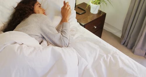 Woman Relaxing in Bed While Using Cell Phone