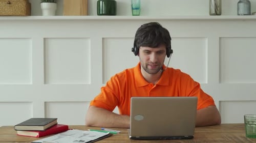 Man Uses a Headset To Talk Online at His Workplace Confident Man Sits at the Office Desk and Looks