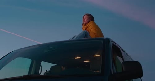 Woman Sitting on Car Roof at Sunset