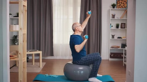 Senior Man Exercising with Dumbbells on Exercise Ball