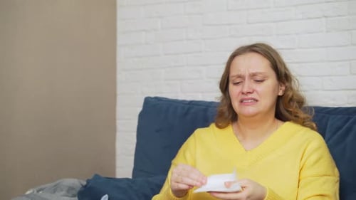 Sad Woman Crying and Blowing Nose on Couch