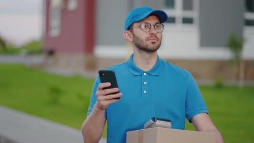 Delivery Man Using Smartphone With Box In Hand