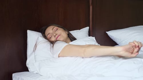 Woman Lying in Bed Waking Up and Stretching