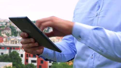 Junger gutaussehender Geschäftsmann arbeitet auf Tablet - Stadt (Gebäude) im Hintergrund - Nahaufnahme