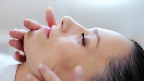 Closeup Face of Young Beautiful Woman Relaxing and Enjoying Beauty Contouring Massage at Clinic