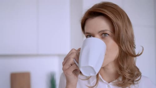 Woman Drinking from Mug in Kitchen Close Up