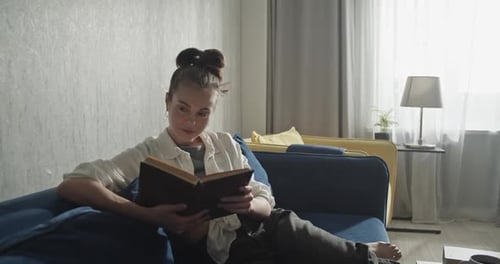 Woman Reading Book on Couch in Living Room