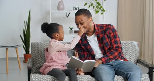 Smiling Father Reads Story to Young Daughter