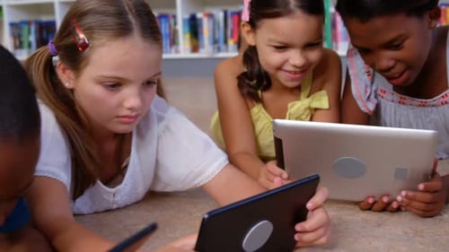 School kids and teacher using digital tablet in library