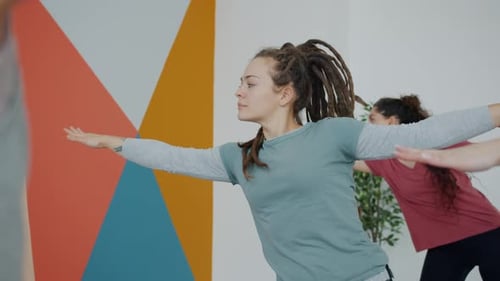 Good-looking Girl Hipster Training in Sports Center Doing Yoga with Group of Women