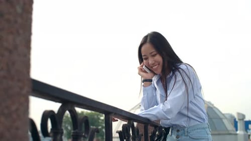 Woman Talking on Cellphone on a Balcony