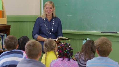 Teacher reads book to kids in school classroom
