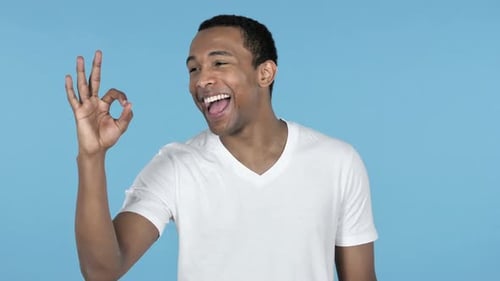 Man Gives OK Sign on Blue Background