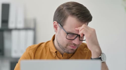 Close Up of Young Man with Laptop Having Headache in Office