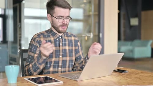 Young Designer Doing Video Chat on Laptop in Modern Office