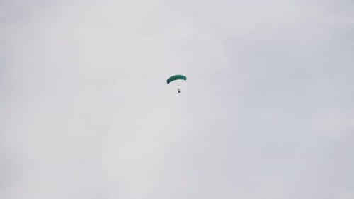 Skydiver Descends with Parachute in Overcast Sky