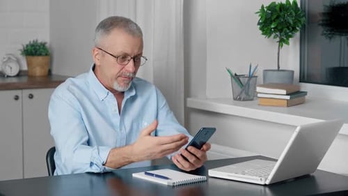 Surprised Man Using Mobile Phone at Desk