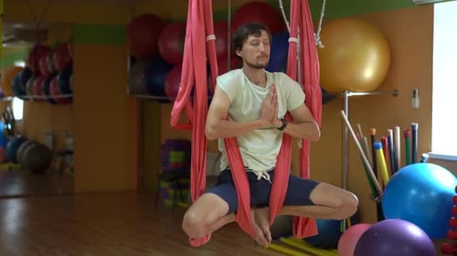 Man Practices Aerial Yoga in the Gym