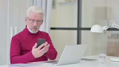 Senior Man Using Smartphone at Desk