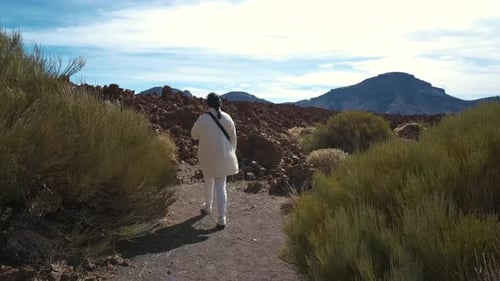 Touristin spaziert durch die Berge erstarrter Lava im Teide-Vulkan-Nationalpark am
