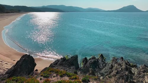 Eine malerische Meereslandschaft einer blauen Lagune mit einem leeren öffentlichen Strand bei Sonnenaufgang Rocky Coast