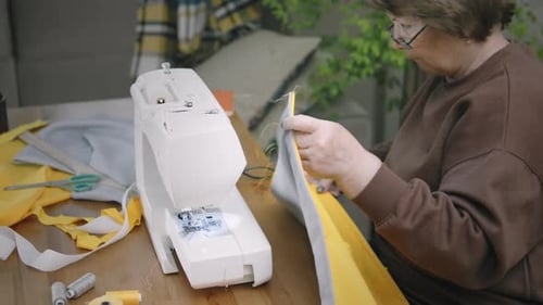 Woman Sewing Fabric at Home Sewing Machine