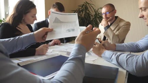 Group of Young Businessmen Sitting at Table in Modern Office and Working on New Project. Colleagues