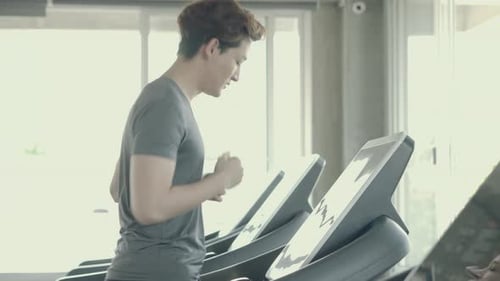 Handsome asian young man exercise with running on treadmill in the gym.