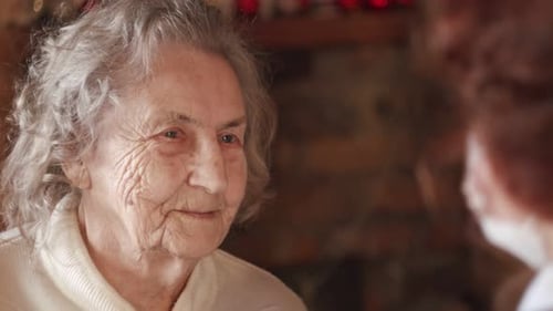 Senior Woman Listens to Friend Indoors