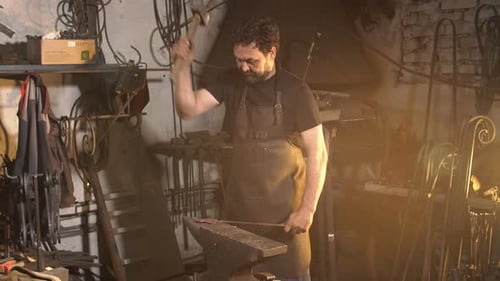 Man Works with Molten Metal in the Forge.