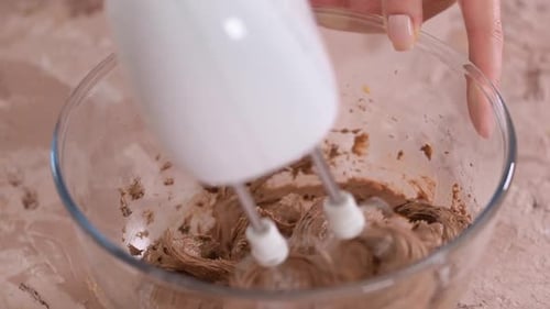Electric Mixer Mixing Chocolate Frosting in Glass Bowl