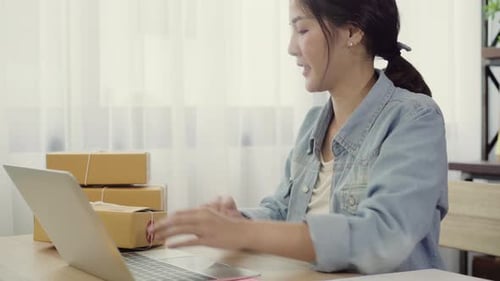 Woman Typing on Laptop with Boxes in Office