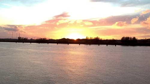 Drone flies towards the sunset of golden orange cloudscape.