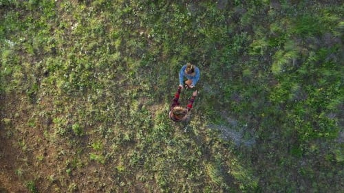 Rising aerial view looking down at two girls dancing in a forest