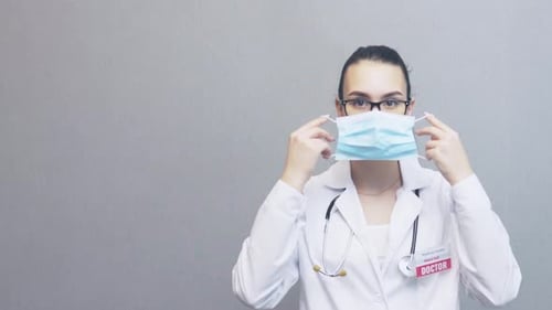 Female Doctor Putting on Surgical Mask in Studio