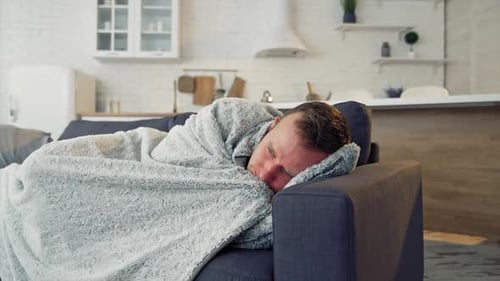 Homme malade sous une couverture chaude sur un canapé confortable à la maison. Pandémie. Concept de quarantaine.