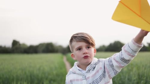 Boy With Paper Airplane in Green Field