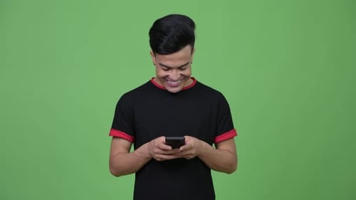 Young Adult Using Mobile Phone on Green Background