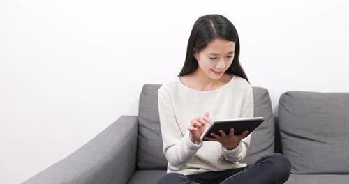 Woman Using Tablet on Couch in Home
