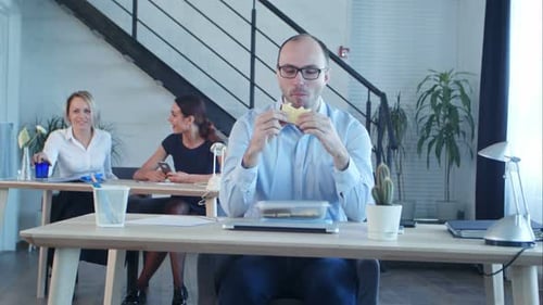 Young Business Man Sitting with Sandwich in Office