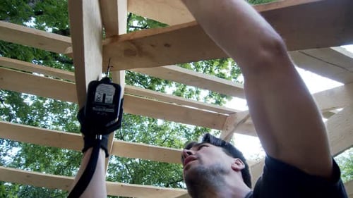 the Man Runs a Screw Twists the Screw Into the Roof of His Garage and Looks Satisfied