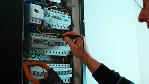 Electrician Testing Electrical Panel with Tester and Multimeter