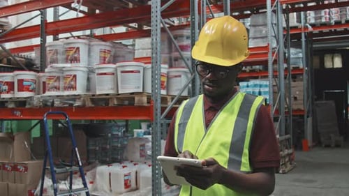 Busy Black Male Warehouse Worker with Tablet