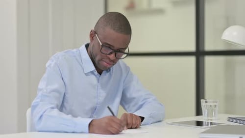 Man Writing at Desk in Office