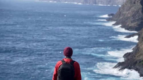 Solo Hiker Overlooking Rugged Ocean Coastline