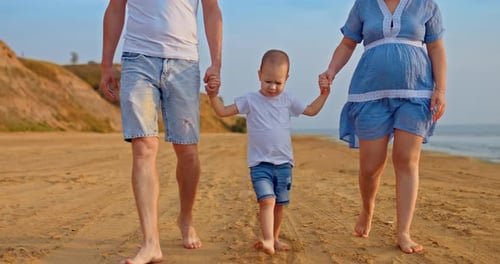 Loving Family Walking on Sandy Beach at Sunset