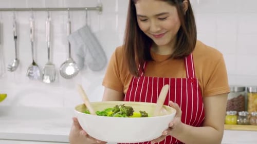 Woman Prepares Fresh Salad in Bright Kitchen