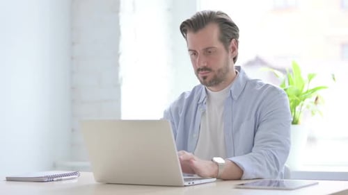 Man Uses Laptop at Desk Gives Thumbs Up